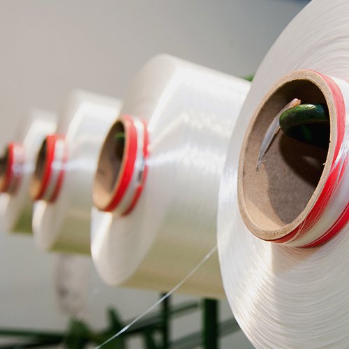 Gulungan benang Polyester putih pada mesin pemrosesan benang sebagai bahan baku pembuatan tali