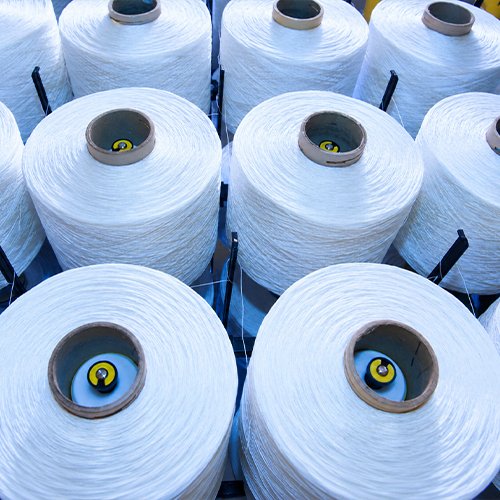 Gulungan benang POY (Partially Oriented Yarn) putih sebagai bahan baku produksi tali talikur di Mukti Djaya Talikur