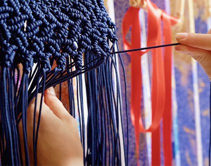Proses menganyam talikur bahan PP (Polypropylene) untuk membuat tas rajut berwarna biru navy